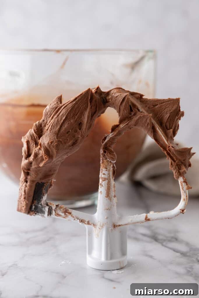 Whipped chocolate buttercream on a paddle attachment, showing its creamy texture.