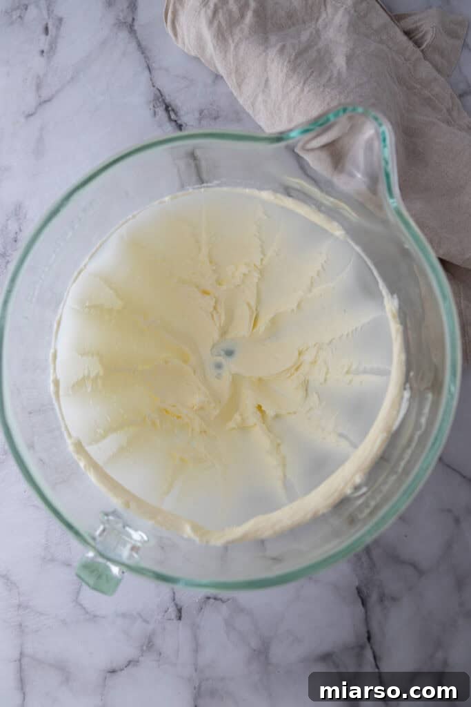 Softened butter being beaten by an electric mixer in a bowl.