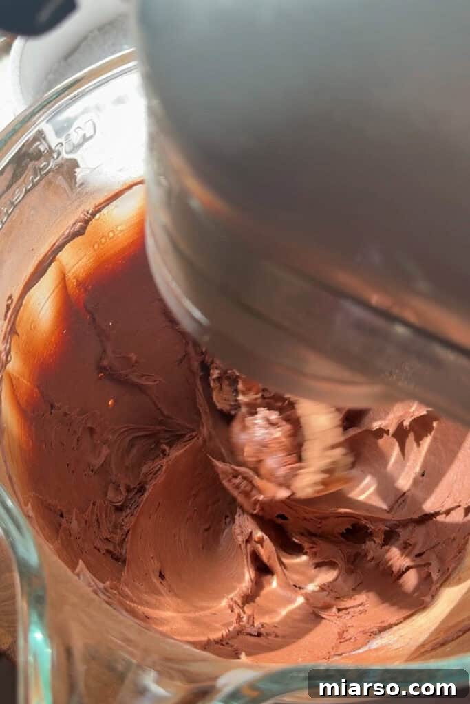 Ingredients being mixed together in a bowl to form chocolate frosting.