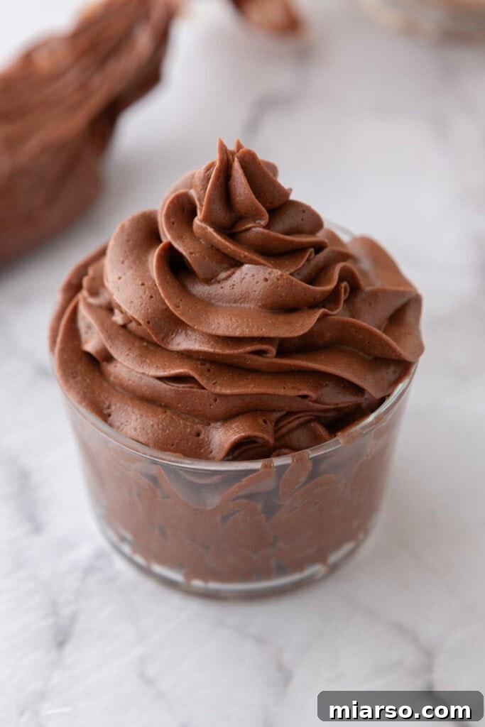 A cup of rich, dark one-bowl chocolate buttercream recipe ready for use.