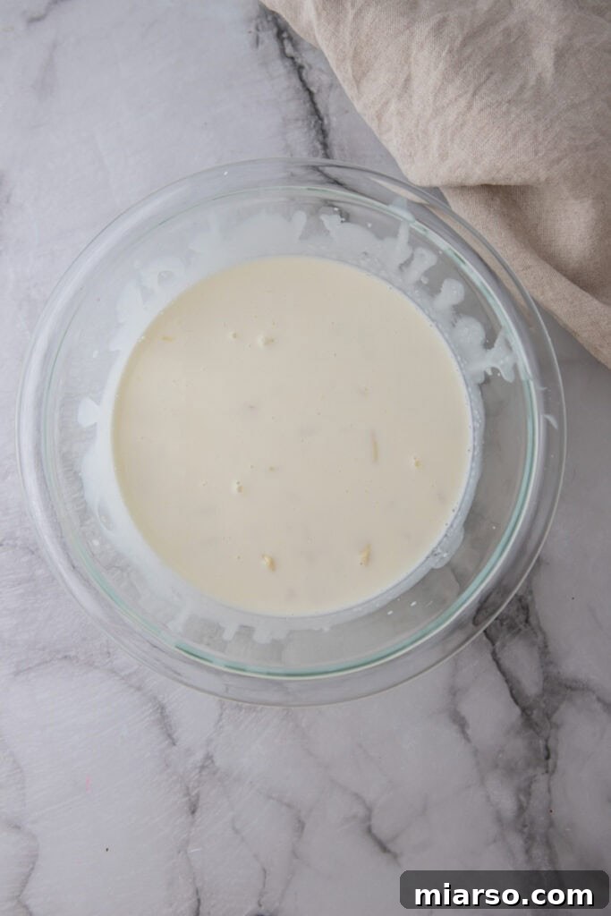 hot cream poured over chopped white chocolate in a bowl