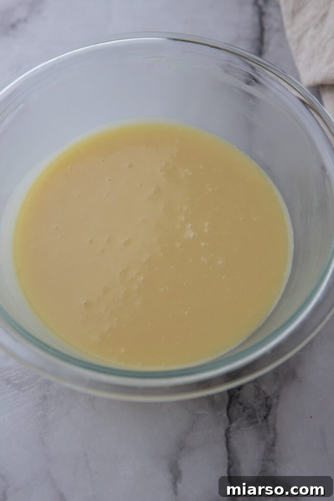 ingredients for white chocolate ganache in a bowl, stirred