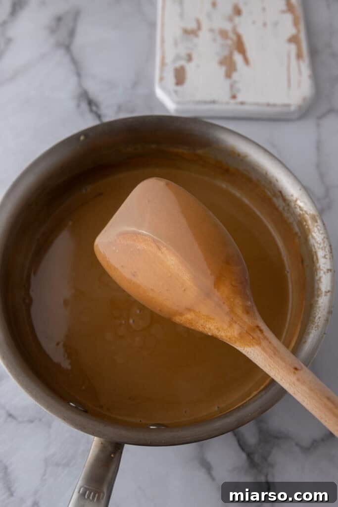 The back of a wooden spoon coated in thickened custard, demonstrating readiness