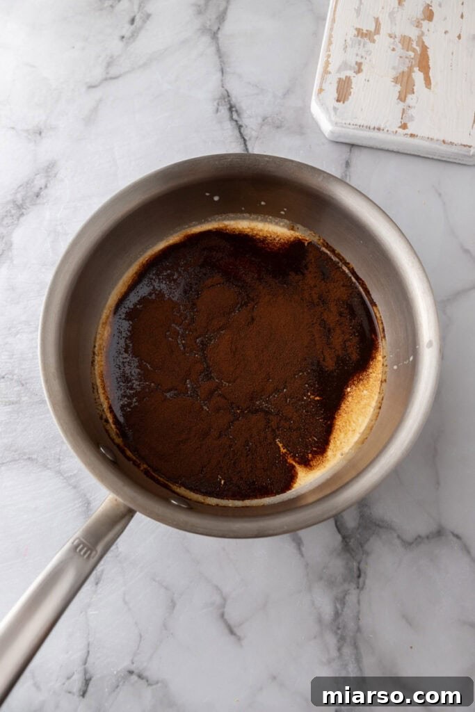 Heavy cream, milk, and espresso powder in a saucepan on the stove
