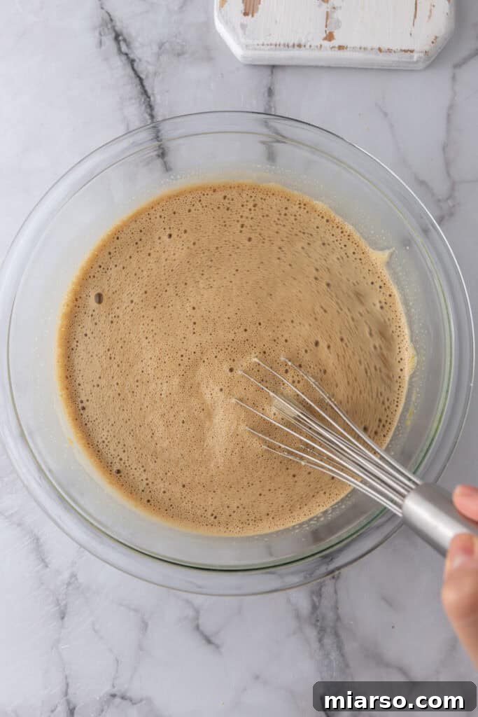 Slowly pouring warm cream into egg yolk mixture for tempering