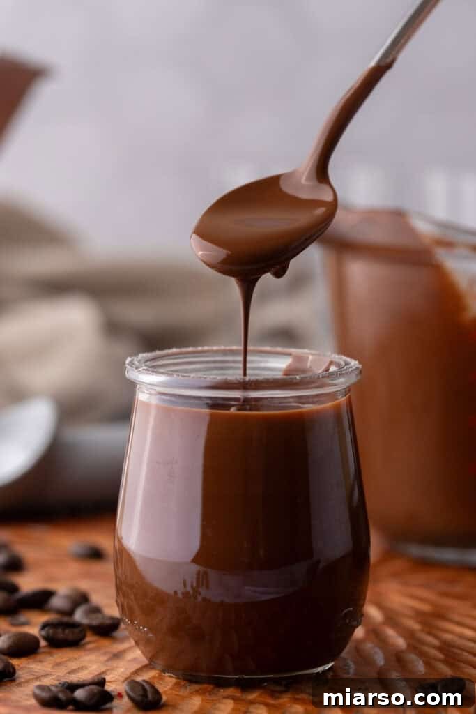 Easy 5-Minute Magic Chocolate Shell for Ice Cream 2 Spoon scooping melted chocolate and coconut oil mixture, ready to pour over ice cream.