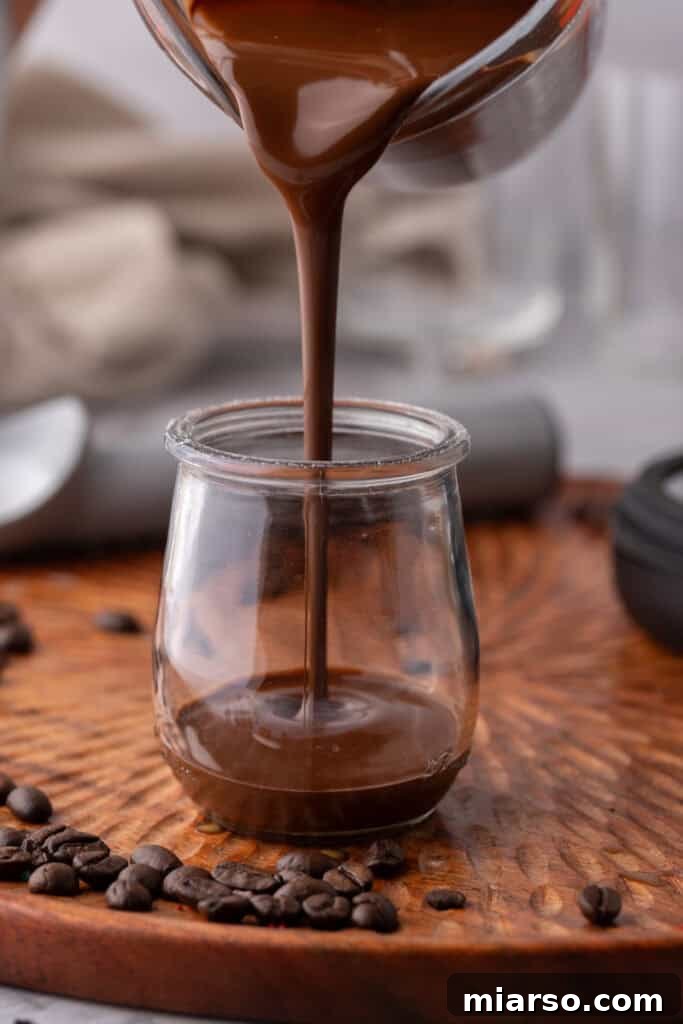 Easy 5-Minute Magic Chocolate Shell for Ice Cream 7 Pouring melted magic chocolate shell into a serving jar.