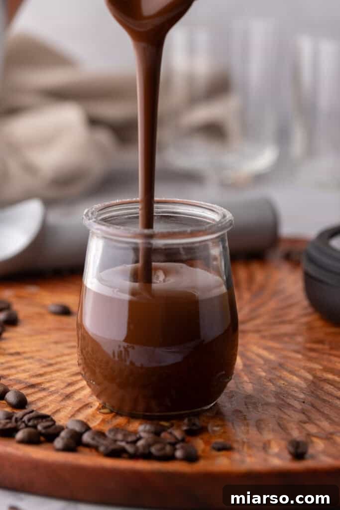 Easy 5-Minute Magic Chocolate Shell for Ice Cream 8 Close-up of pouring melted chocolate magic shell into a jar.