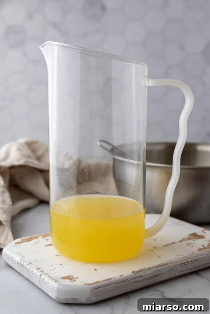 Adding cold water to the lemon syrup in a pitcher
