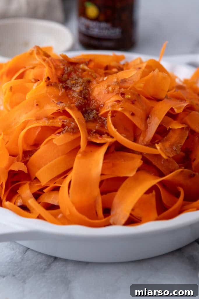 A close-up of the finished Carrot Ribbon Salad, showing perfectly coated, vibrant carrot ribbons ready to eat.