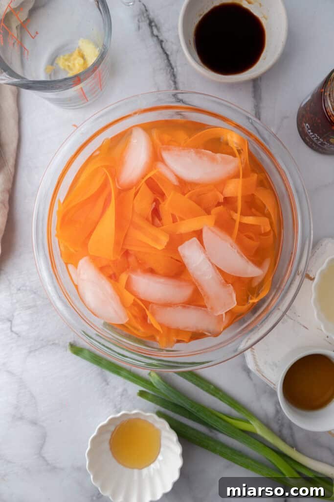Close-up of a vegetable peeler shaving delicate carrot ribbons into a bowl.