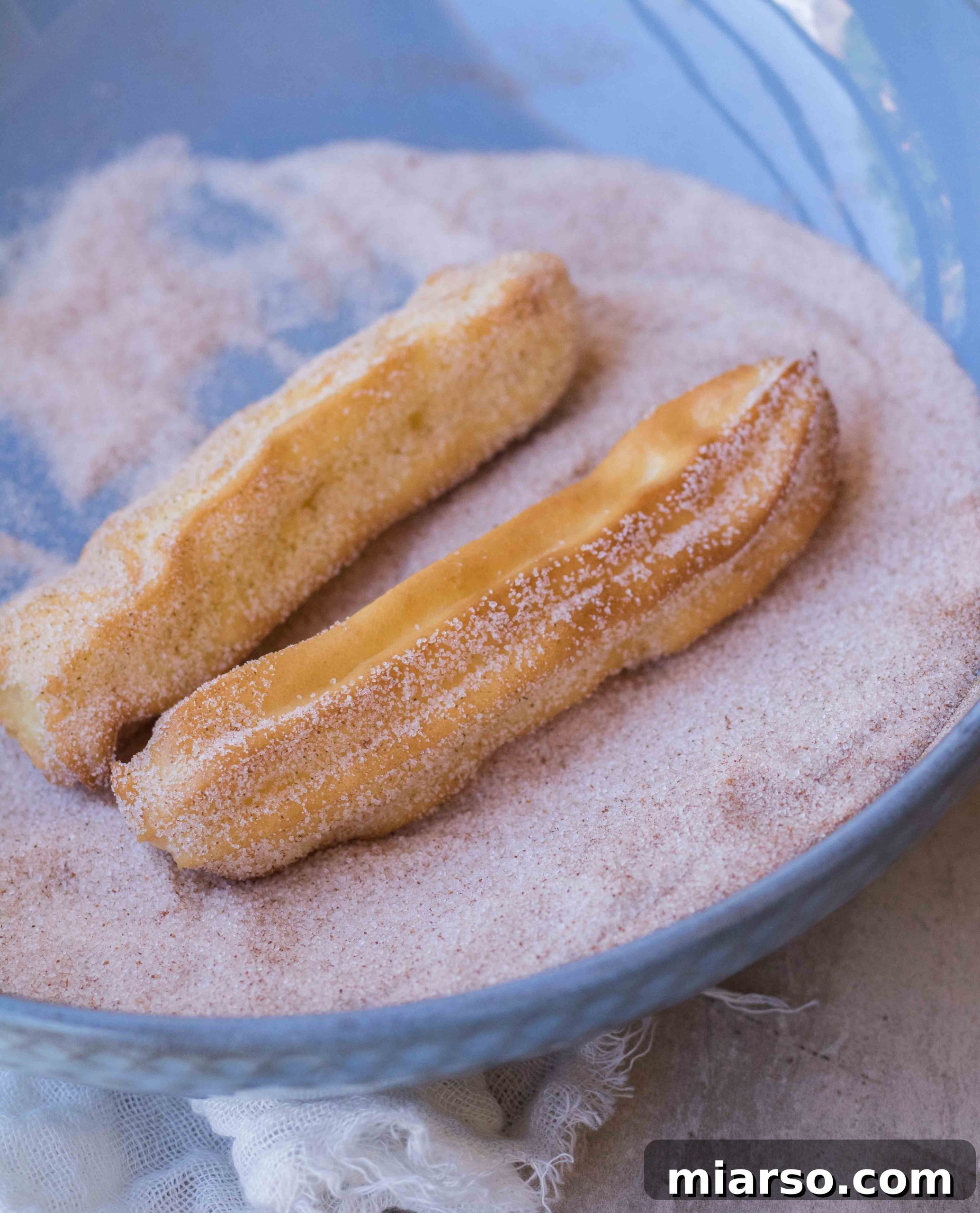 Air fried churros cooking in the air fryer basket, turning golden.