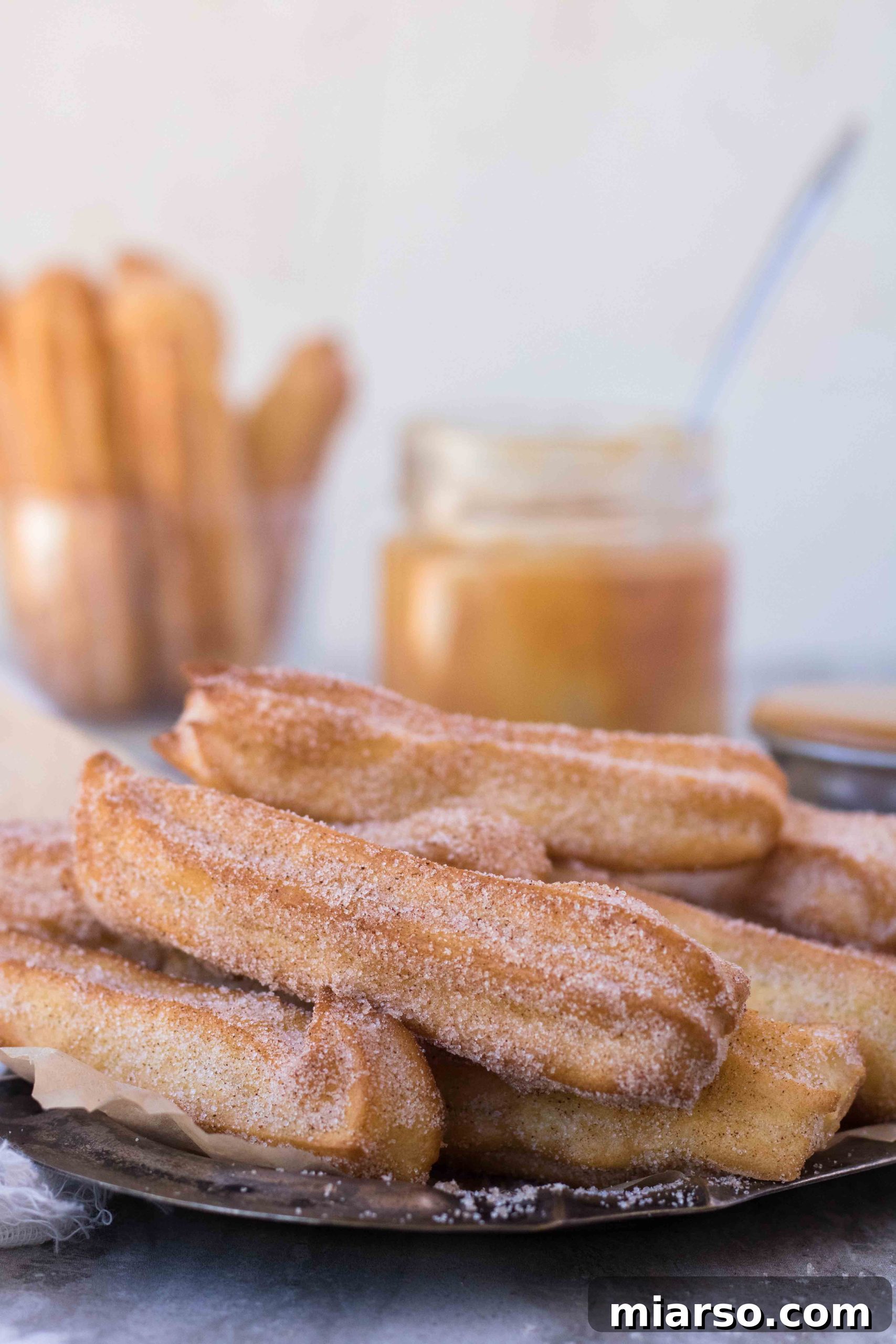 Air fryer churros coated in cinnamon sugar, served with dulce de leche dip.
