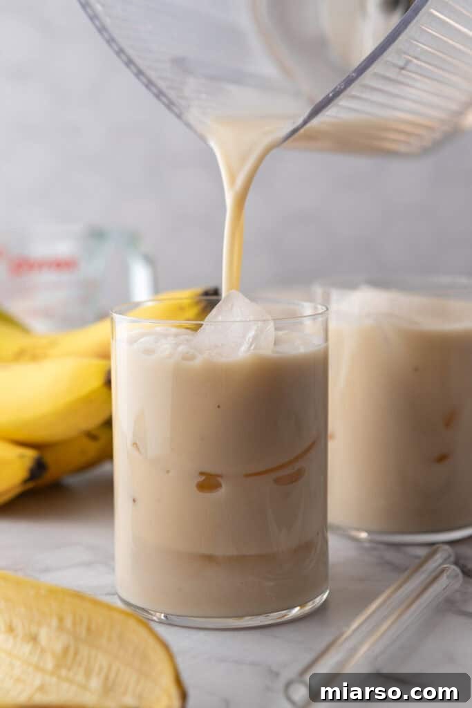 Korean Banana Milk being poured into a tall glass with ice