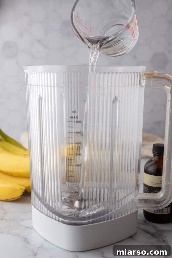 Banana, milk, and water being added to a blender