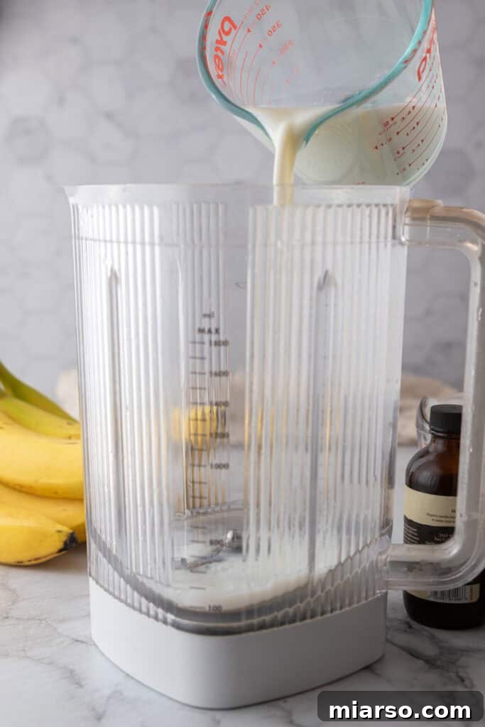 Milk being poured into a blender with bananas
