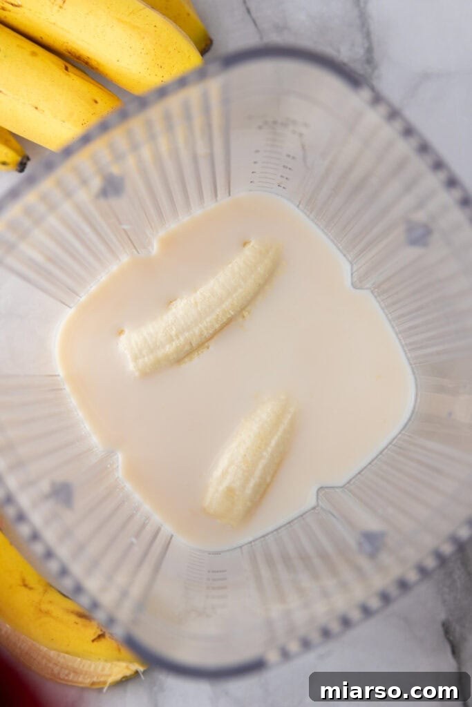 Vanilla extract being added to a blender for banana milk