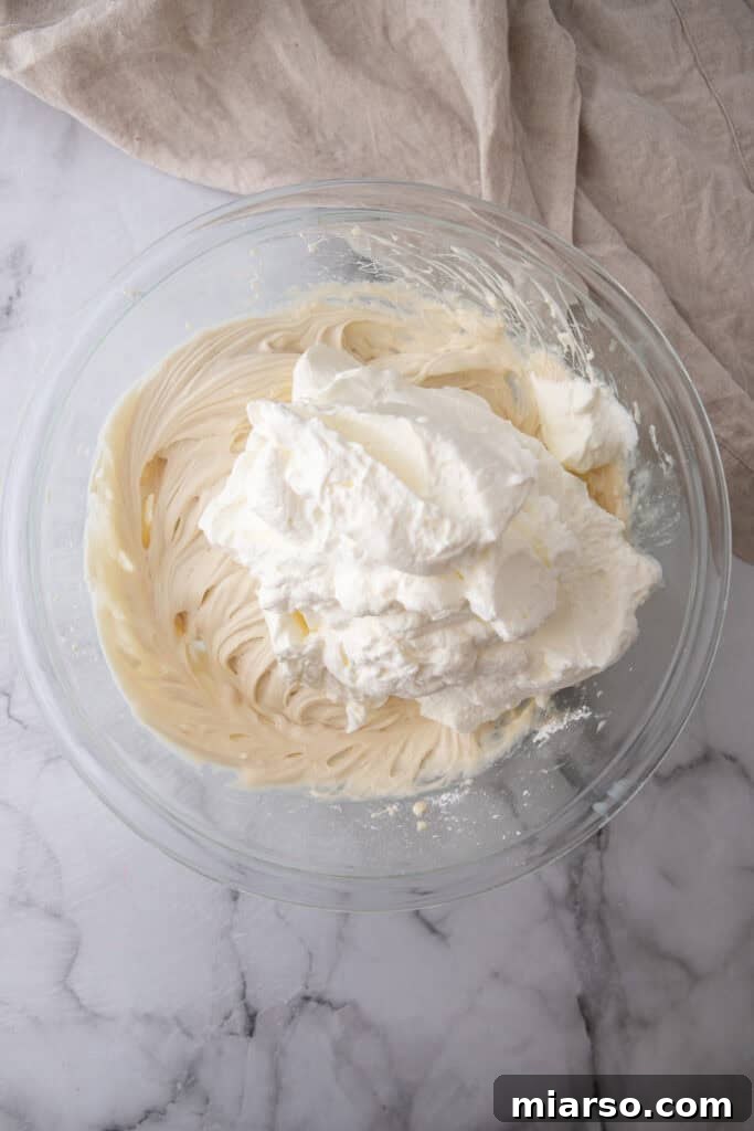 Whipped cream being gently folded into the cream cheese mixture