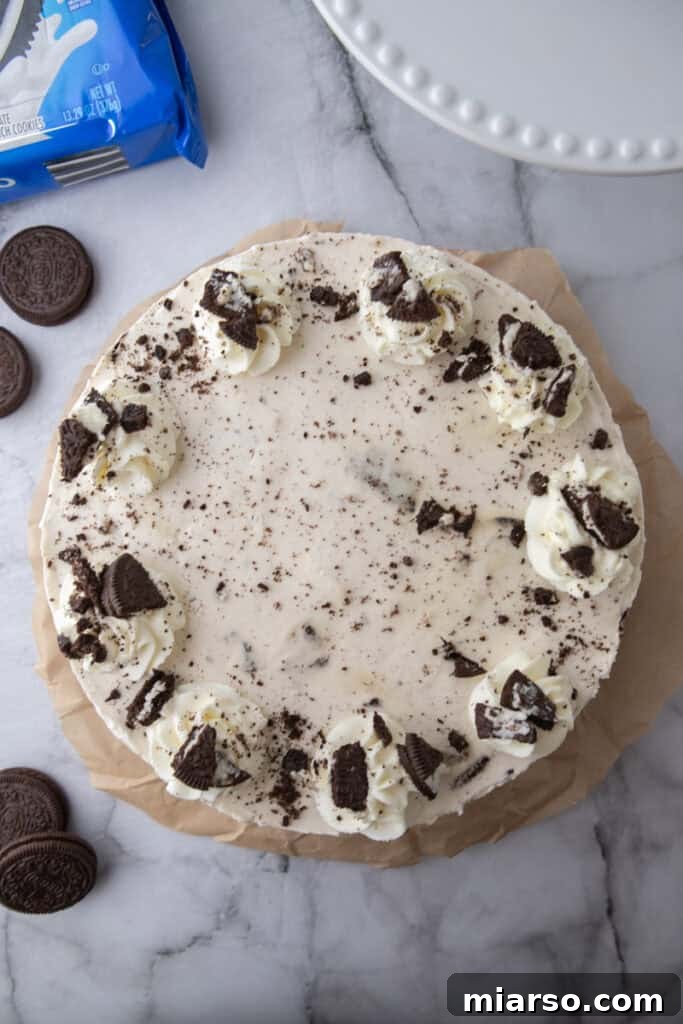 No Bake Oreo Cheesecake presented on a cake stand, decorated with whipped cream and Oreos