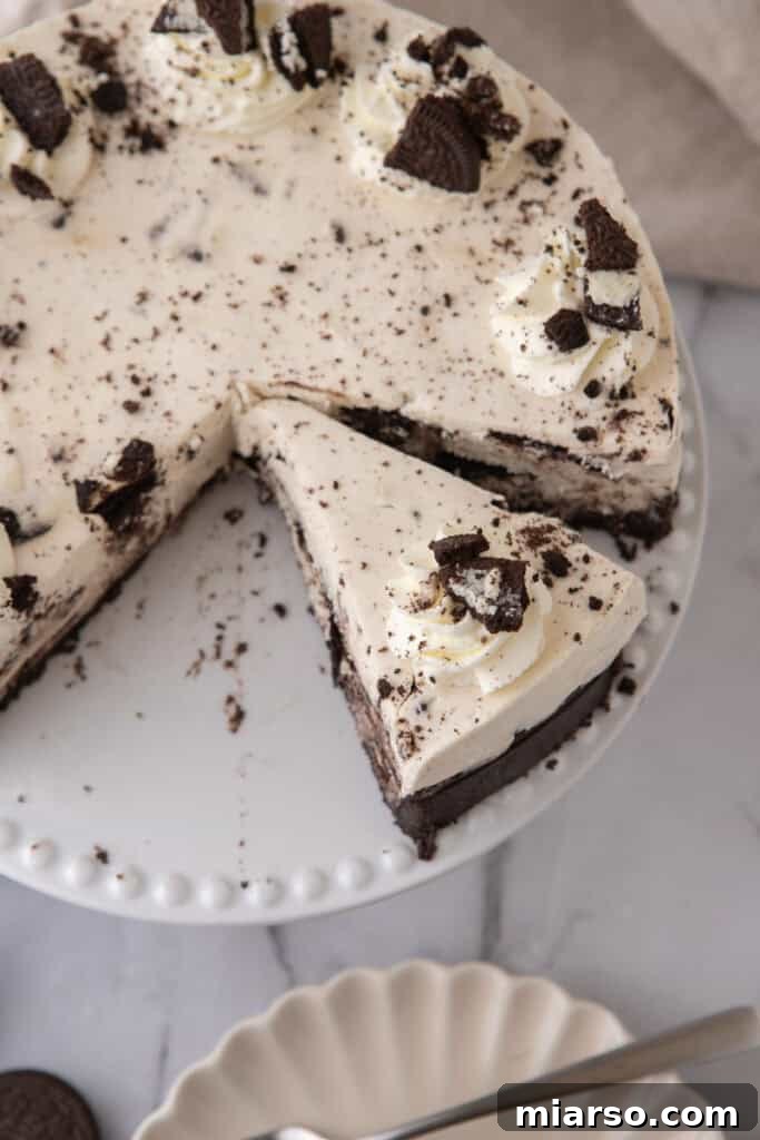 A side view of a slice of No Bake Oreo Cheesecake on a plate, showing the distinct crust and filling layers