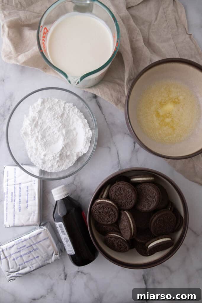 Individual ingredients laid out for No Bake Oreo Cheesecake, including Oreos, butter, cream cheese, and heavy cream
