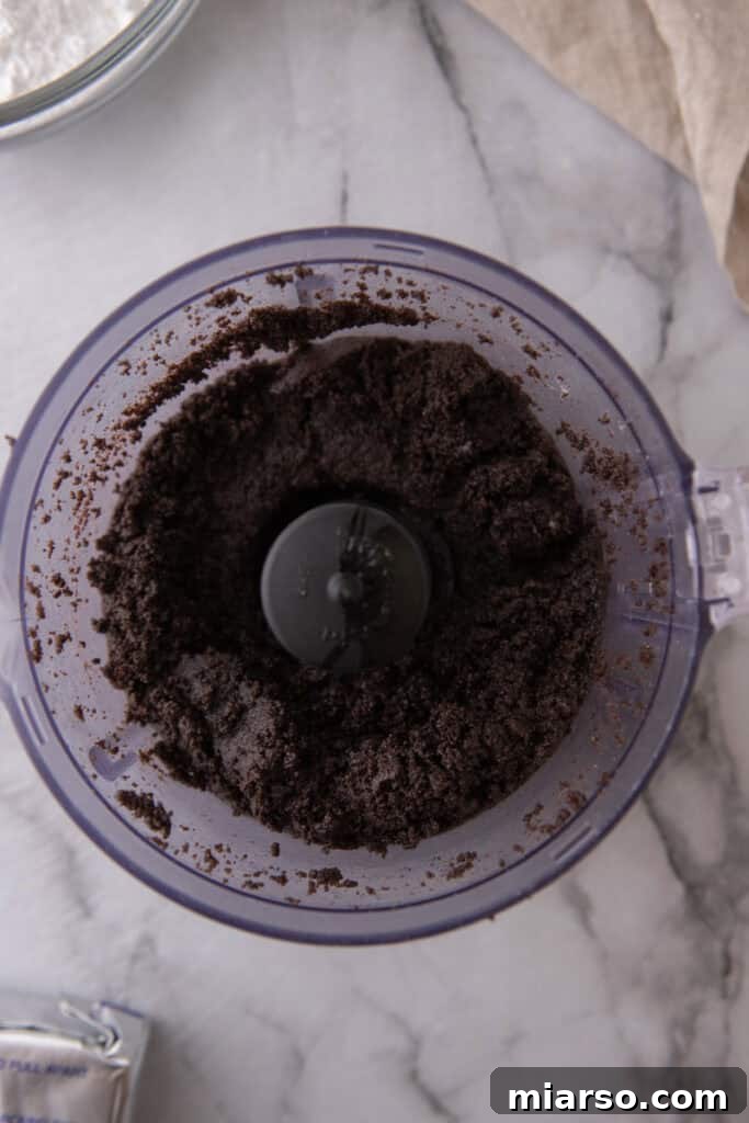 Crushed Oreo cookies mixed with melted butter in a bowl