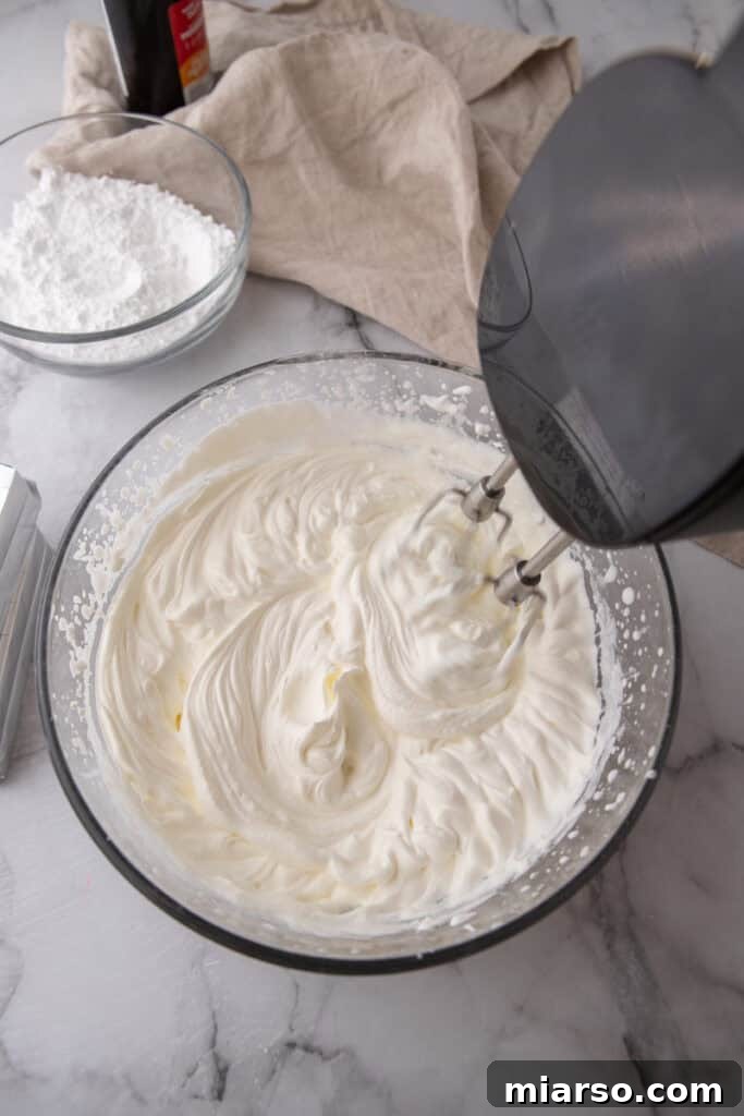 Heavy whipping cream being whipped to stiff peaks in a separate bowl