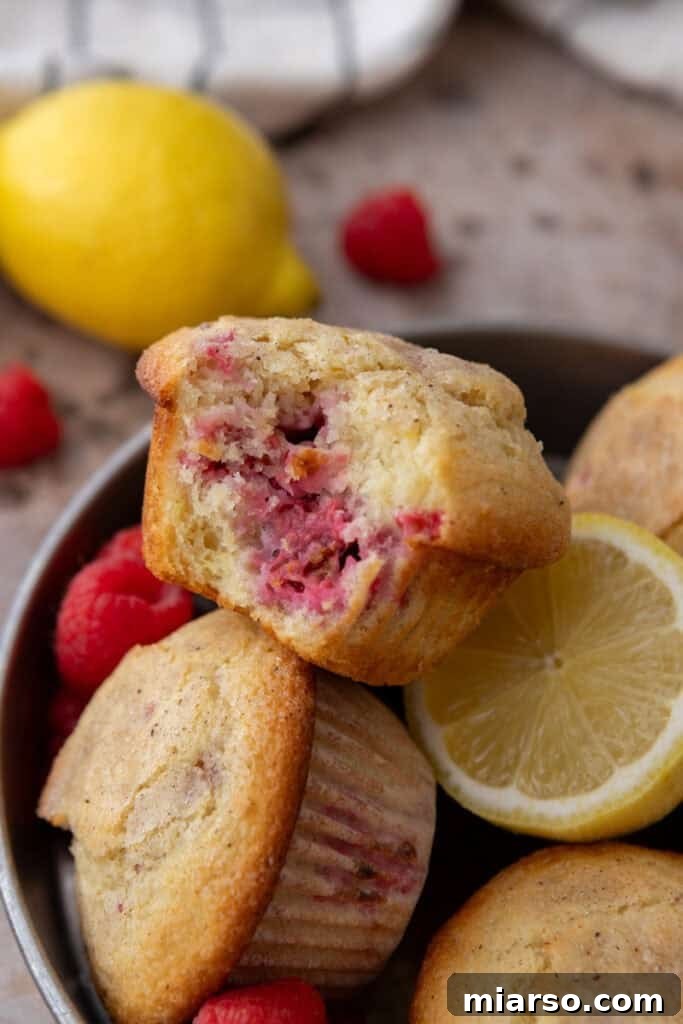 Lemon Raspberry muffins split in half, showcasing the fluffy texture and juicy raspberries inside.