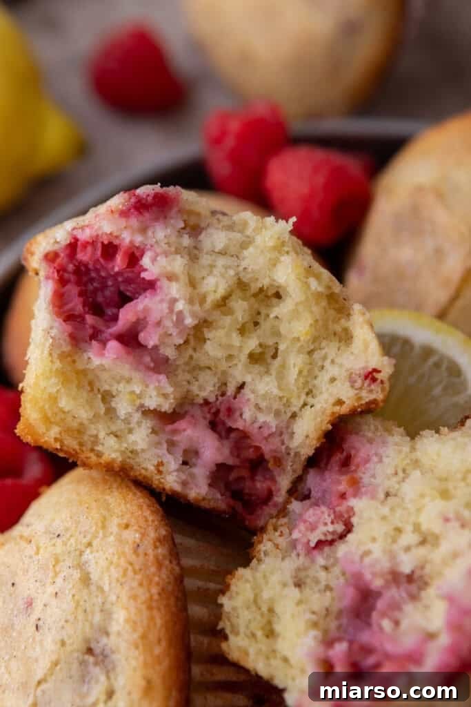 A lemon raspberry muffin carefully split in half, revealing its moist interior and fruit.