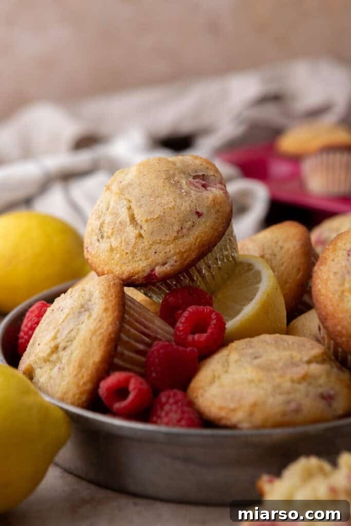 A side view of a stack of fluffy lemon raspberry muffins.