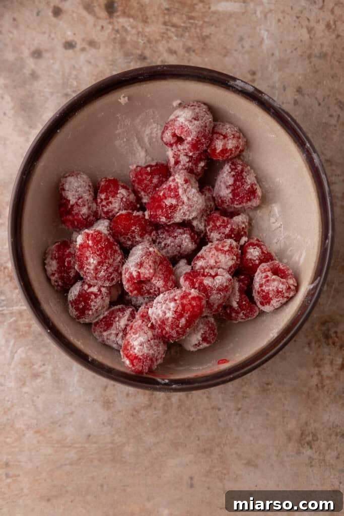 Raspberries being tossed in flour to prevent sinking in the batter.