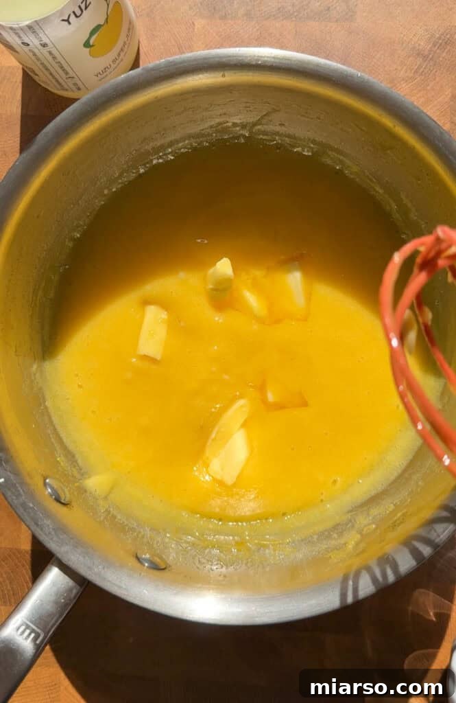 Adding butter pieces to the cooked yuzu curd