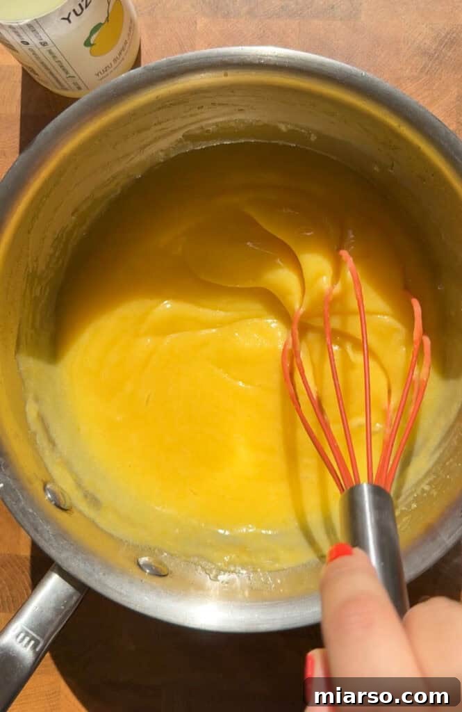 Whisking butter into the yuzu curd until smooth and glossy