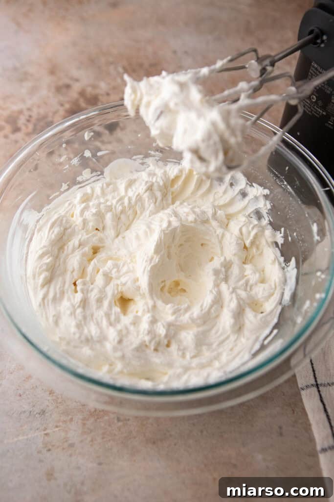 Heavy cream being whipped to stiff peaks in a separate bowl