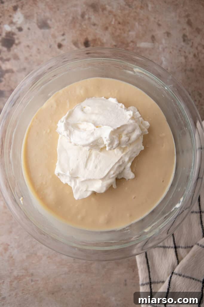 First addition of whipped cream being folded into the cream cheese base