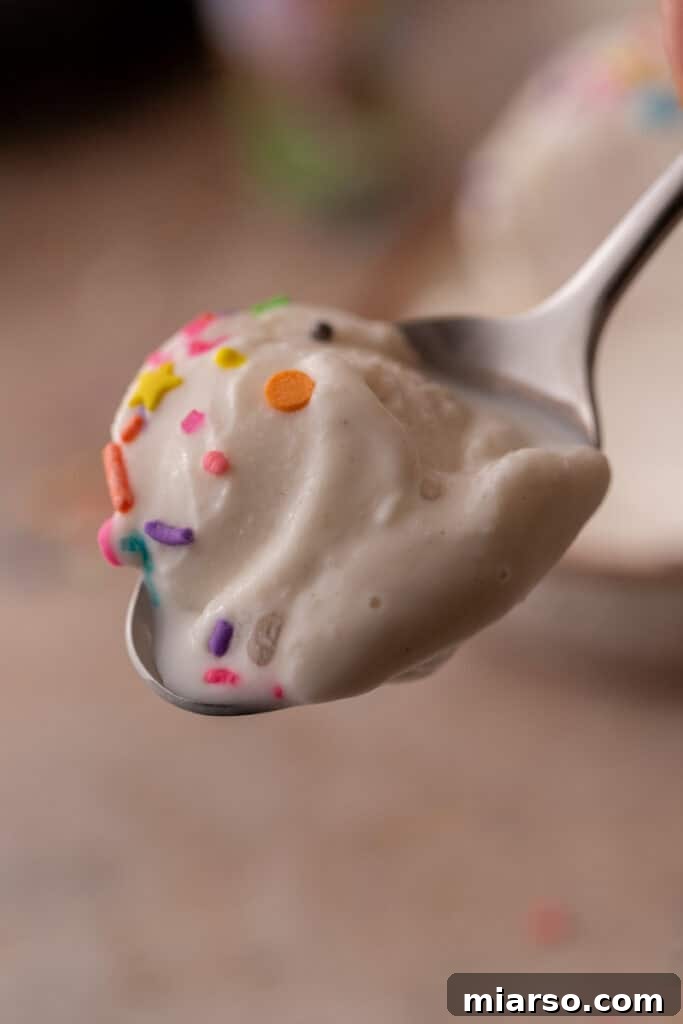 A scoop of high-protein cottage cheese Ninja Creami ice cream being lifted from the pint, showcasing its smooth texture.