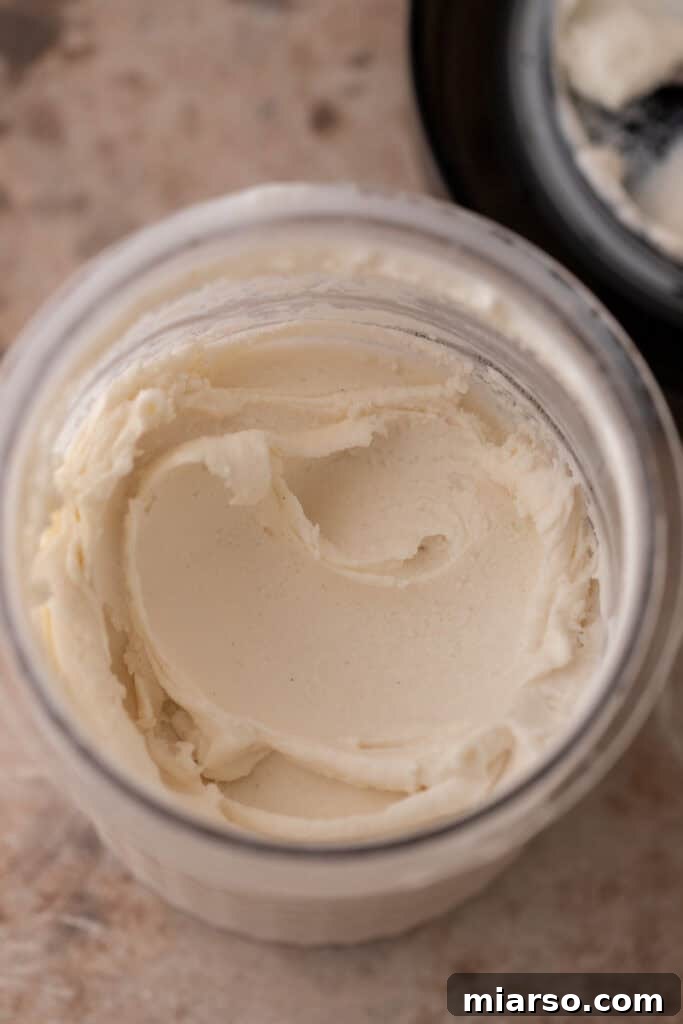 Close-up of cottage cheese and other ingredients in a Ninja Creami container, ready for blending.