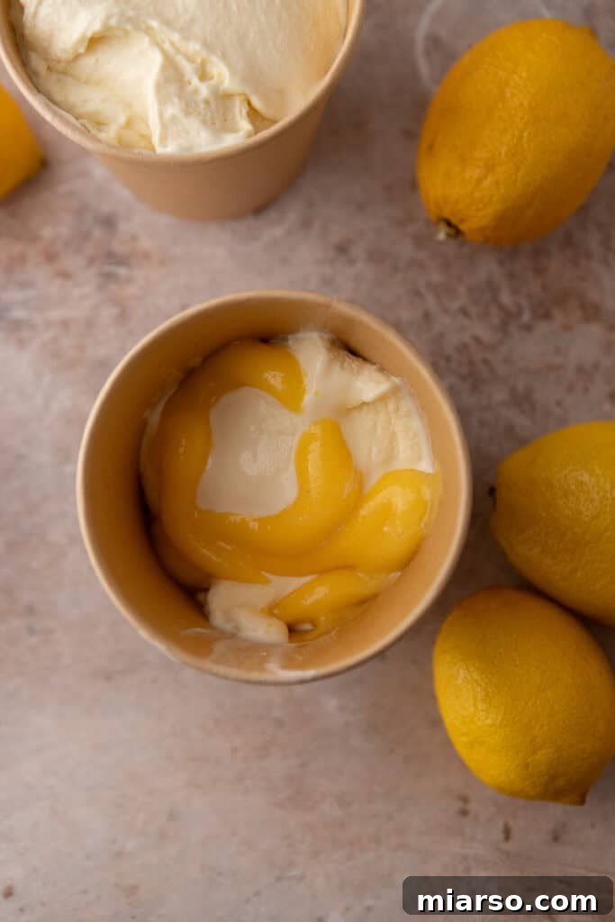 Layering lemon ice cream with dollops of lemon curd in a freezer container.