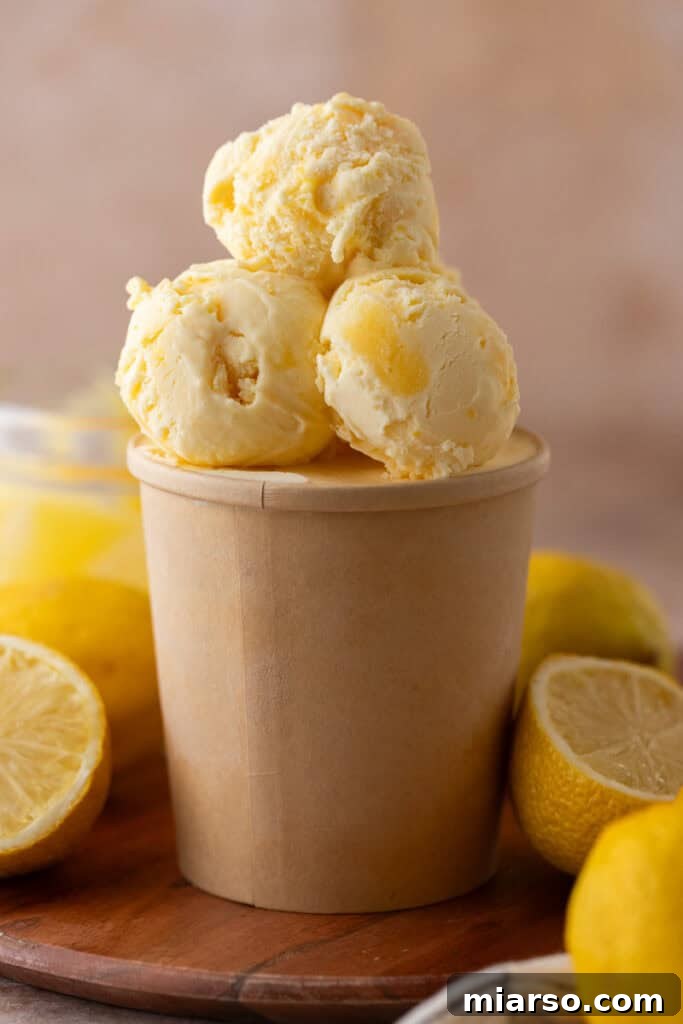 Three scoops of lemon ice cream in a serving glass, garnished with fresh mint and lemon slices.