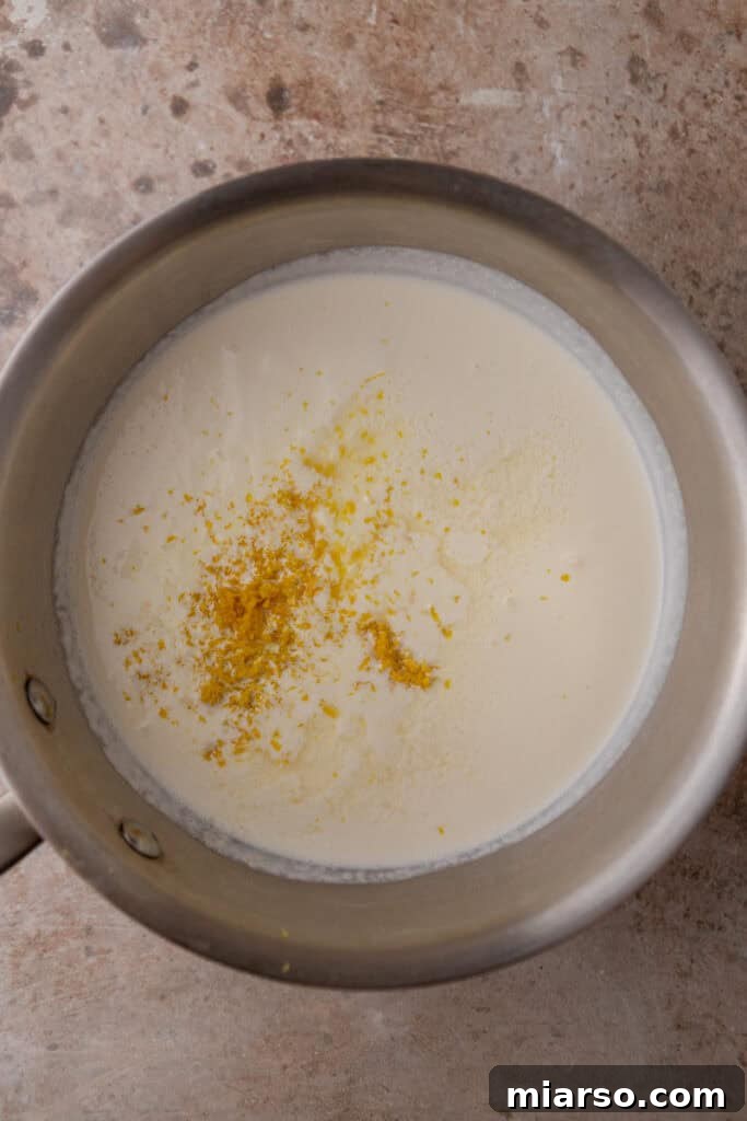 Milk, cream, sugar, and lemon zest heating in a saucepan for the ice cream base.