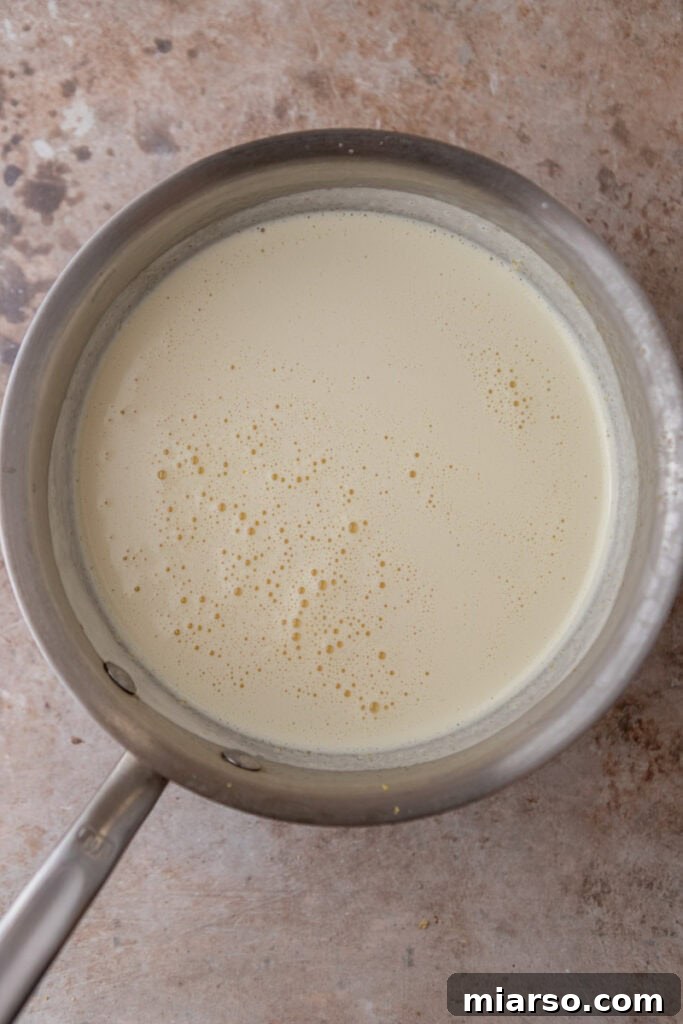 Custard base being strained through a sieve for a smooth texture.