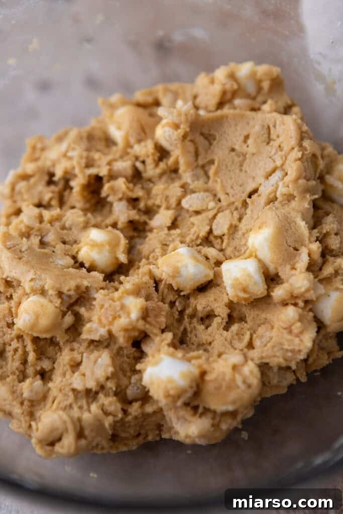 Chilled rice krispy marshmallow cookie dough in a bowl, ready for scooping and baking.