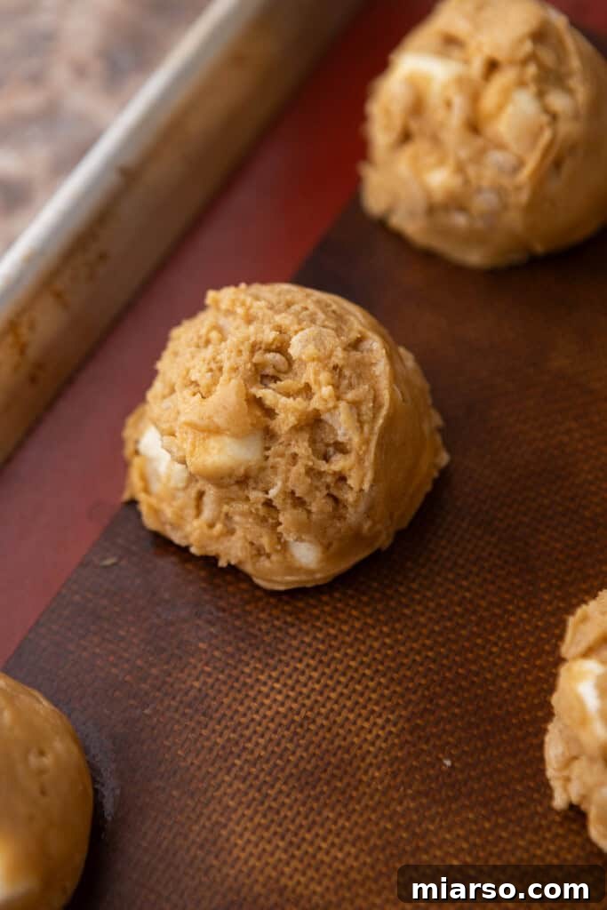 Scooped portions of cookie dough arranged on a parchment-lined baking sheet, ready for the oven.