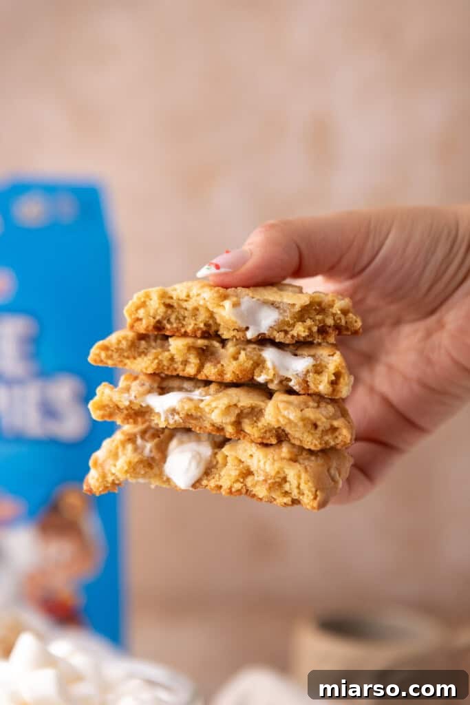 Two Costco Marshmallow Crispy Cookies, one bitten to reveal its chewy interior and melted marshmallow, next to a glass of milk.