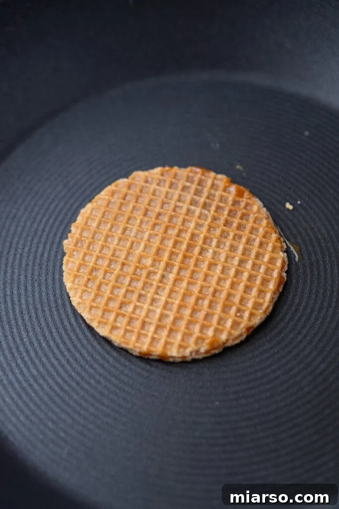 A stroopwafel cookie being warmed in a pan