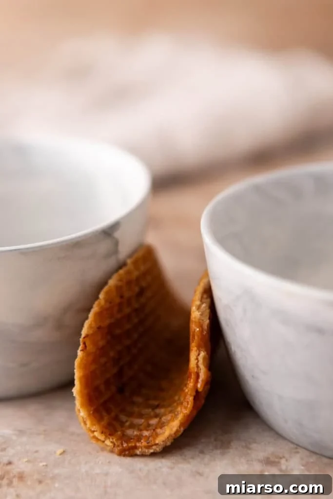Multiple stroopwafels cooling and setting in taco shapes in a muffin tin