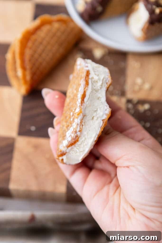 A stroopwafel taco being filled with vanilla ice cream