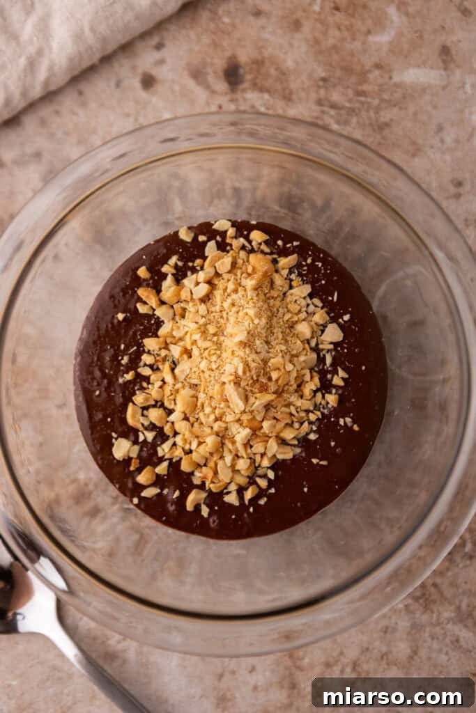 Melted chocolate and chopped peanuts being mixed together