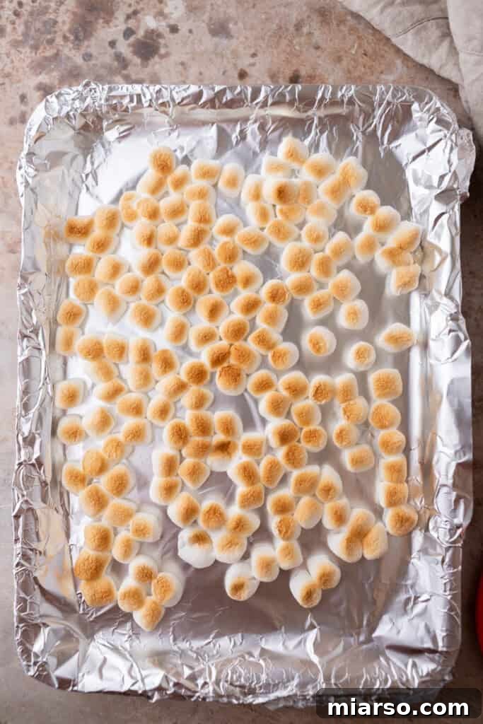 Mini marshmallows spread evenly on a baking sheet, ready for toasting.