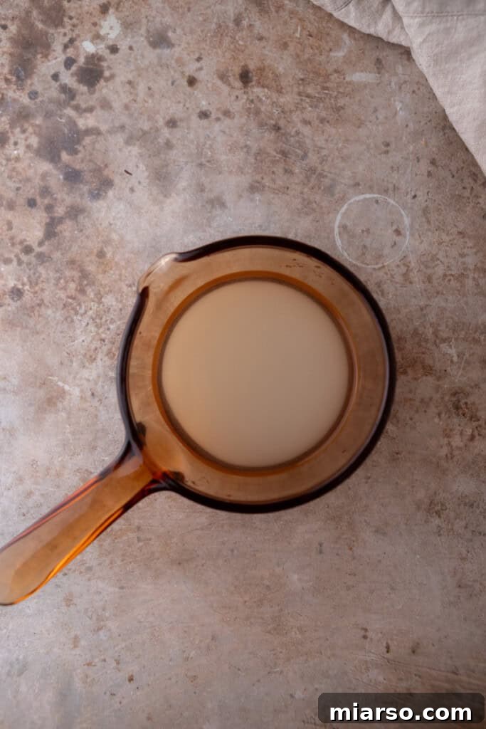 Water and granulated sugar combined in a saucepan, beginning to simmer for the syrup base.